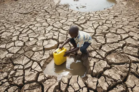 Un jeune garçon dans le lit à sec d'une rivière, illustrant de manière frappante les défis liés à la pénurie d'eau.